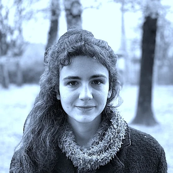 Portrait of Ekin Bozkurt outdoors among trees, in blue-toned black and white